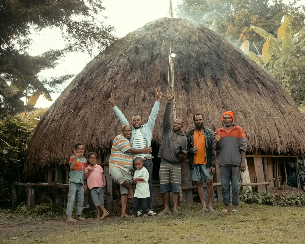 Dani family in front of a honai near Wamena